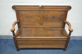 AN OAK HALL SETTLE, with double carved panels, open armrests and lift up seat, length 134cm x