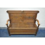 AN OAK HALL SETTLE, with double carved panels, open armrests and lift up seat, length 134cm x