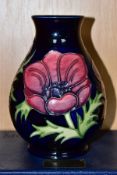 A BOXED MOORCROFT POTTERY BALUSTER VASE, decorated with pink and purple anemone on a dark blue