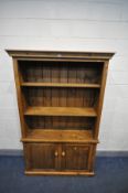 A STAINED PINE OPEN BOOKCASE, with two adjustable shelves above double cupboard doors, width 121cm x