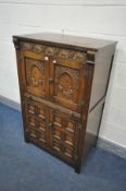 A CARVED OAK TWO DOOR DRINKS CABINETS, with a pull out cutting slide above double cupboard doors,