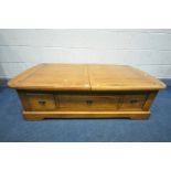 A GOLDEN OAK COFFEE TABLE with double pull out leaves enclosing various pigeon holes, length 140cm x