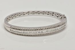 A DIAMOND BANGLE, a white metal hinged bangle set with baguette cut diamonds in a channel setting