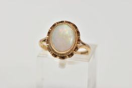 A 9CT GOLD OPAL DRESS RING, designed as an oval cabochon within a collet mount, swag surround,