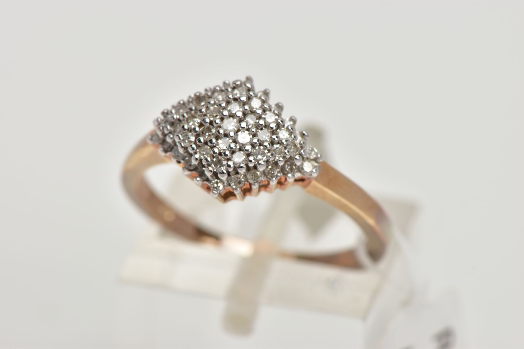 A 9CT GOLD DIAMOND CLUSTER RING, the cluster of a lozenge shape, set with single cut diamonds,