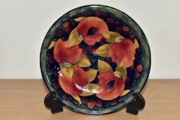 A MOORCROFT POTTERY SHALLOW BOWL, the interior decorated with a pomegranate design on a mottled blue