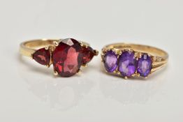 TWO 9CT GOLD GEM SET RINGS, the first designed with a central four claw set, oval cut garnet,