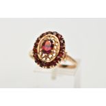 A YELLOW METAL GARNET CLUSTER RING, of an oval form, centring on a six claw set, oval cut garnet,