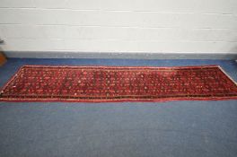 A WOLLEN RED GROND RUNNER, length 368cm x 75cm (condition:-edges fraying)