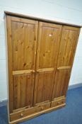 A PINE THREE DOOR WARDROBE, with two drawers, width 127cm x depth 52cm x height 179cm