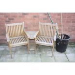 A TEAK CURVED SIDE BY SIDE GARDEN SEATING UNIT with two shelves and a parasol holder to centre