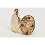 A SILVER GILT LOCKET PENDANT, of an oval form, set with a central oval cut moonstone, with red