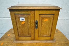 AN EDWARDIAN OAK STATIONERY CABINET, the double doors and hinged top enclosing a fitted interior,