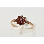 A 9CT GOLD GARNET CLUSTER RING, of a flower shape, set with circular cut garnets, to a plain