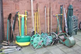A QUANTITY OF GARDEN TOOLS to include rakes, forks, spades etc together with three hose reels, a