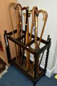 A 1920'S DARK OAK STAINED WOODEN STICK STAND AND CONTENTS, the stand with four barley twist supports
