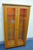 A SOLID GOLDEN OAK TWO DOOR BOOKCASE, with spotlights and four glass shelves, width 95cm x depth