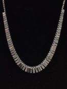 A WHITE METAL COLLAR STYLE NECKLACE, featuring a graduated fringe, with intermittent bark effect and