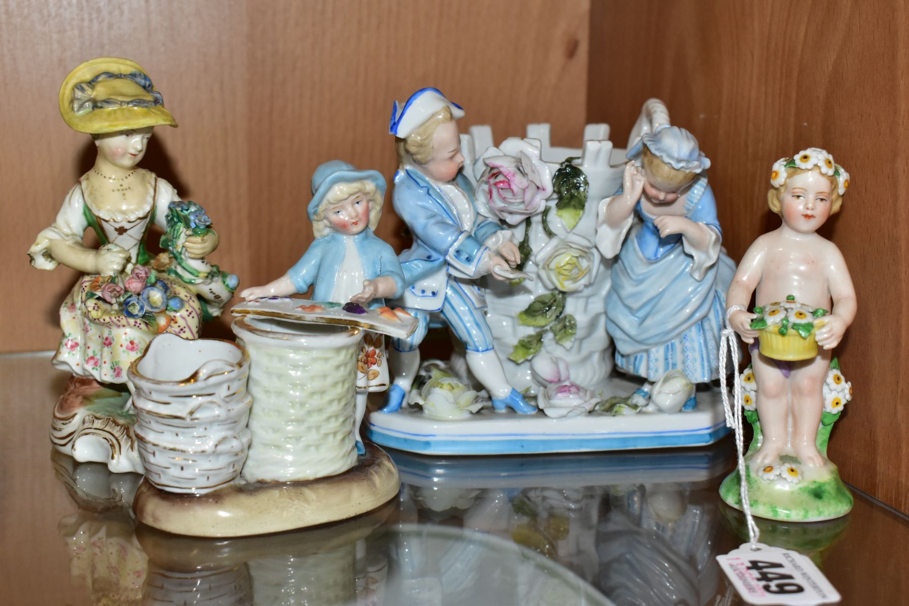 A GROUP OF FOUR 19TH AND 20TH CENTURY PORCELAIN FIGURES, comprising a figure of a putti with