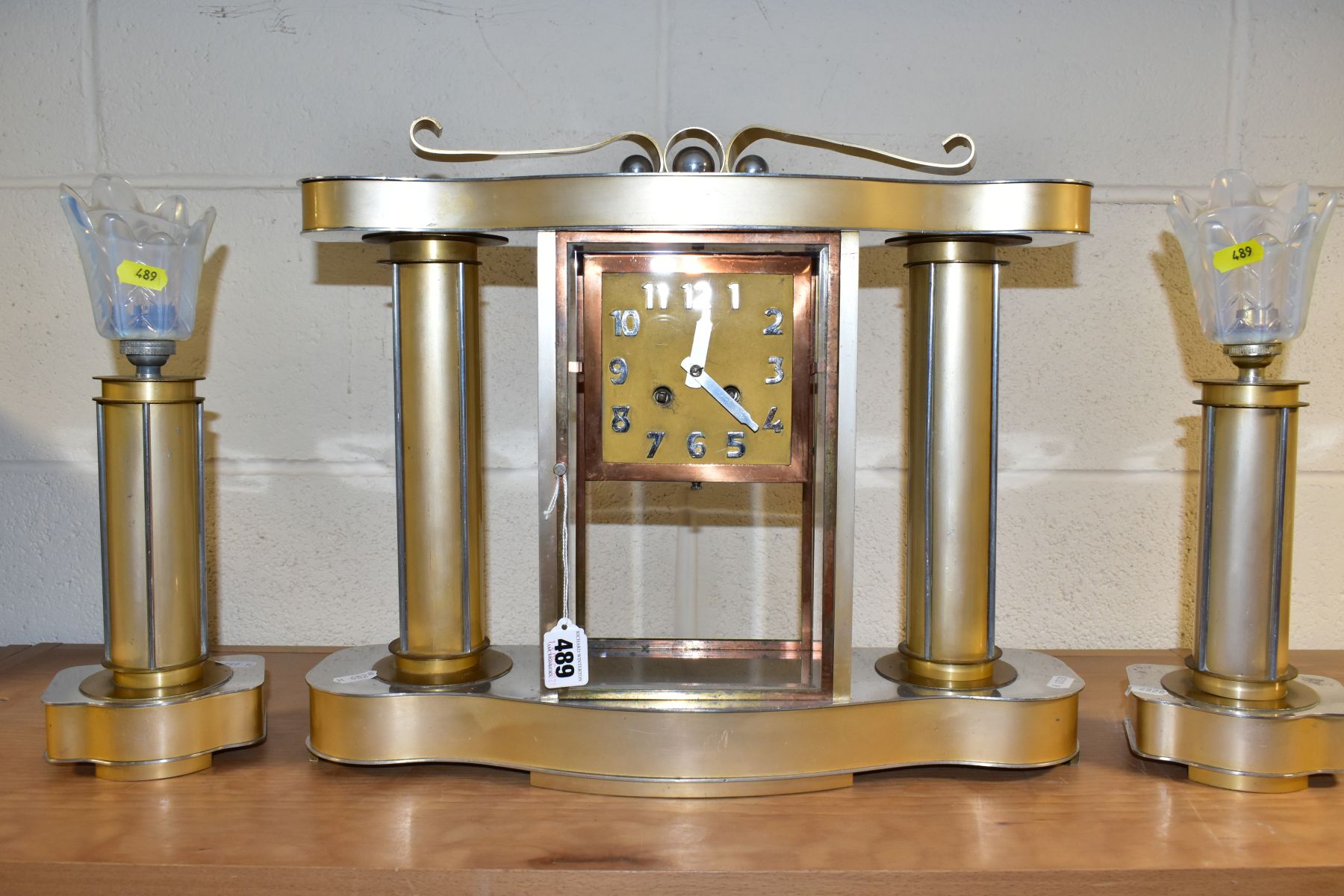 AN ART DECO STYLE CLOCK GARNITURE, the gold coloured metal case with chromed details, Arabic