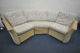 A LIGHT WICKER ROUNDED CONSERVATORY SOFA, with floral cushions, breaks into three sections