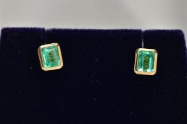 A PAIR OF EMERALD EARRINGS, emerald cut emeralds approximate size 5mm x 4mm, bezel set in a closed