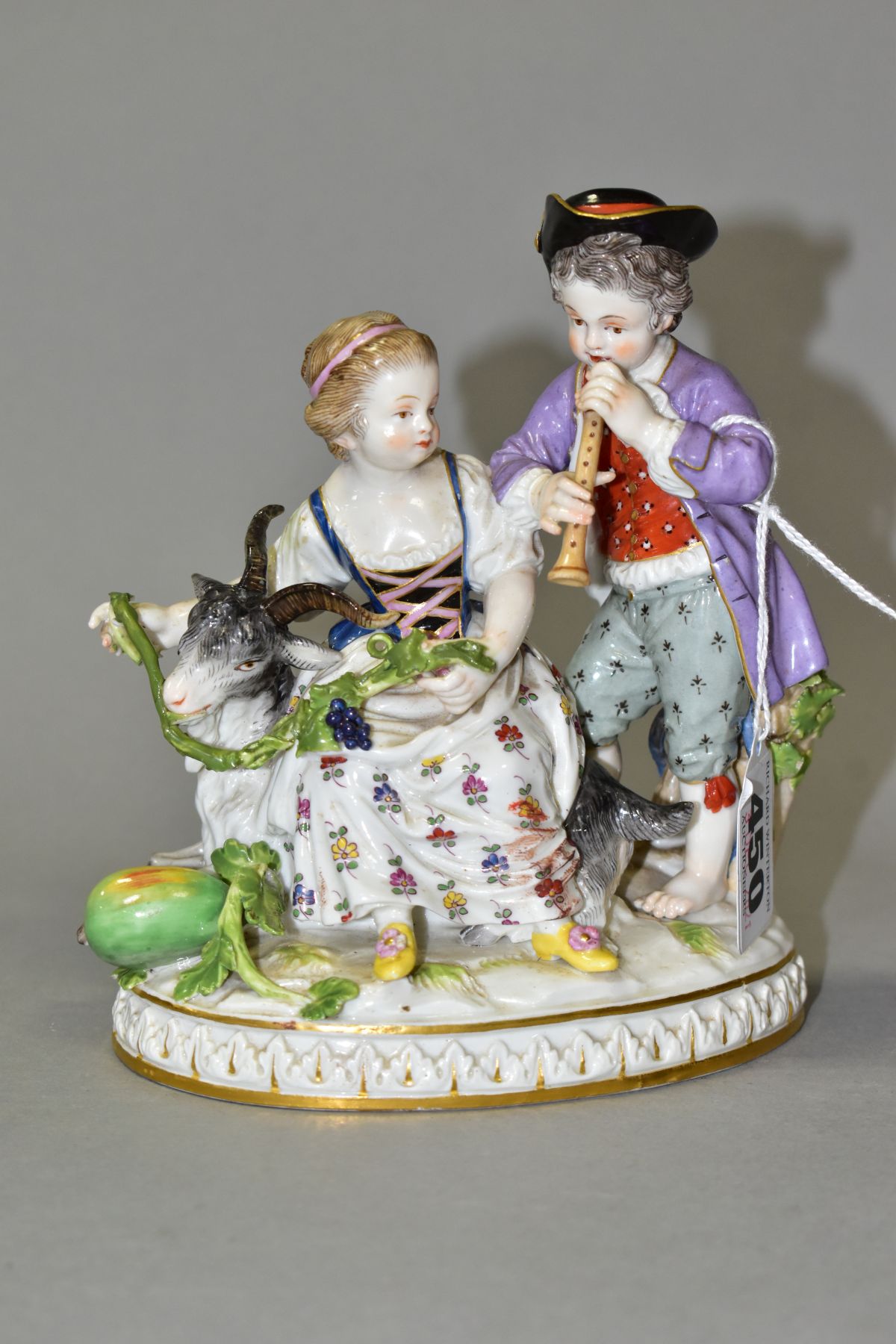 A LATE 19TH CENTURY MEISSEN FIGURE GROUP OF A BOY AND A GIRL WITH A GOAT, the boy playing a wind