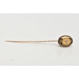 A YELLOW METAL DIAMOND SET STICK PIN, the head of an oval design centring on a star set old cut