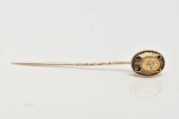 A YELLOW METAL DIAMOND SET STICK PIN, the head of an oval design centring on a star set old cut