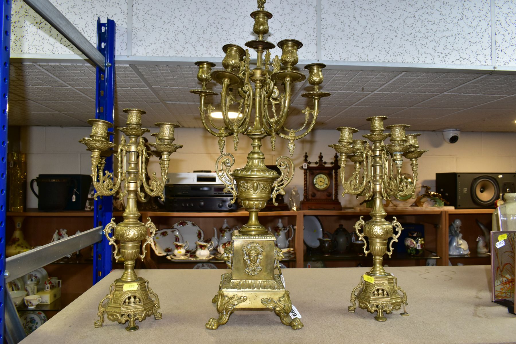 THREE BRASS CANDELABRA, one large candelabrum with five branches around a central sconce, the stem