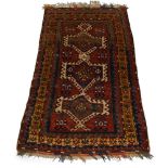 A Kazak rug, mid 20th Century, the red field with three lozenge panels and a signature panel, with