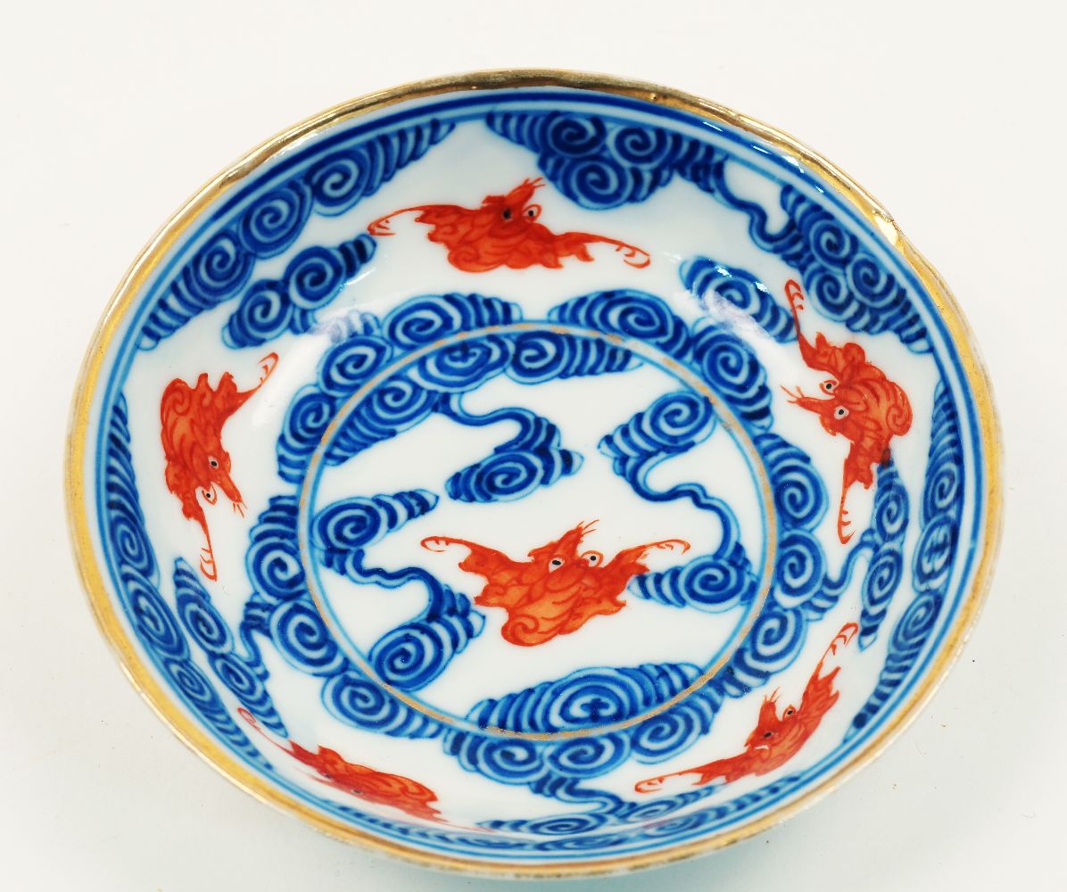 A Chinese porcelain small dish, 19th century, painted in underglaze blue with iron-red bats flying