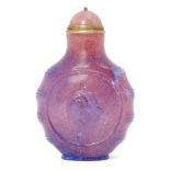 A Chinese pink glass snuff bottle, early 20th century, carved in low relief to each side with a