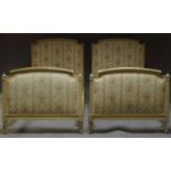 A pair of Louis XVI style cream painted single beds, early 20th Century, with floral upholstered