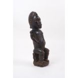 A Yoruba style African wood sculpture of a male figure, 20th century, with ovoid head and carved