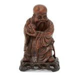 A Chinese hardwood figure of Shou Lao, 19th century, carved holding a peach and standing atop a
