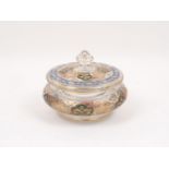 A glass lidded bowl in the Indian style, decorated with gilt floral motifs within coloured glass