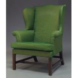 A George III wingback armchair with serpentine wings and loose seat cushion, upholstered in green