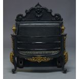 A cast iron fire grate, 20th Century, with shaped back, brass urn finials and applied gilt metal