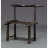 An Ivory Coast carved African chair, 20th Century, with curved back rail on tapered supports to