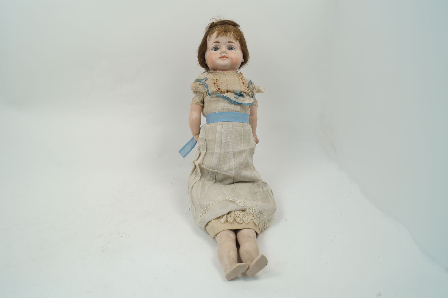 A Victorian composition doll, circa. 1860-70, with brown hair, set with blue glass eyes, fabric body