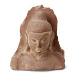 A sandstone fragmentary bust of Buddha, with characteristic long lobed ears and hair pulled to a top