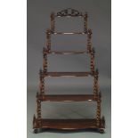 A Victorian rosewood six tier whatnot, with six graduated serpentine tiers, on spiral turned