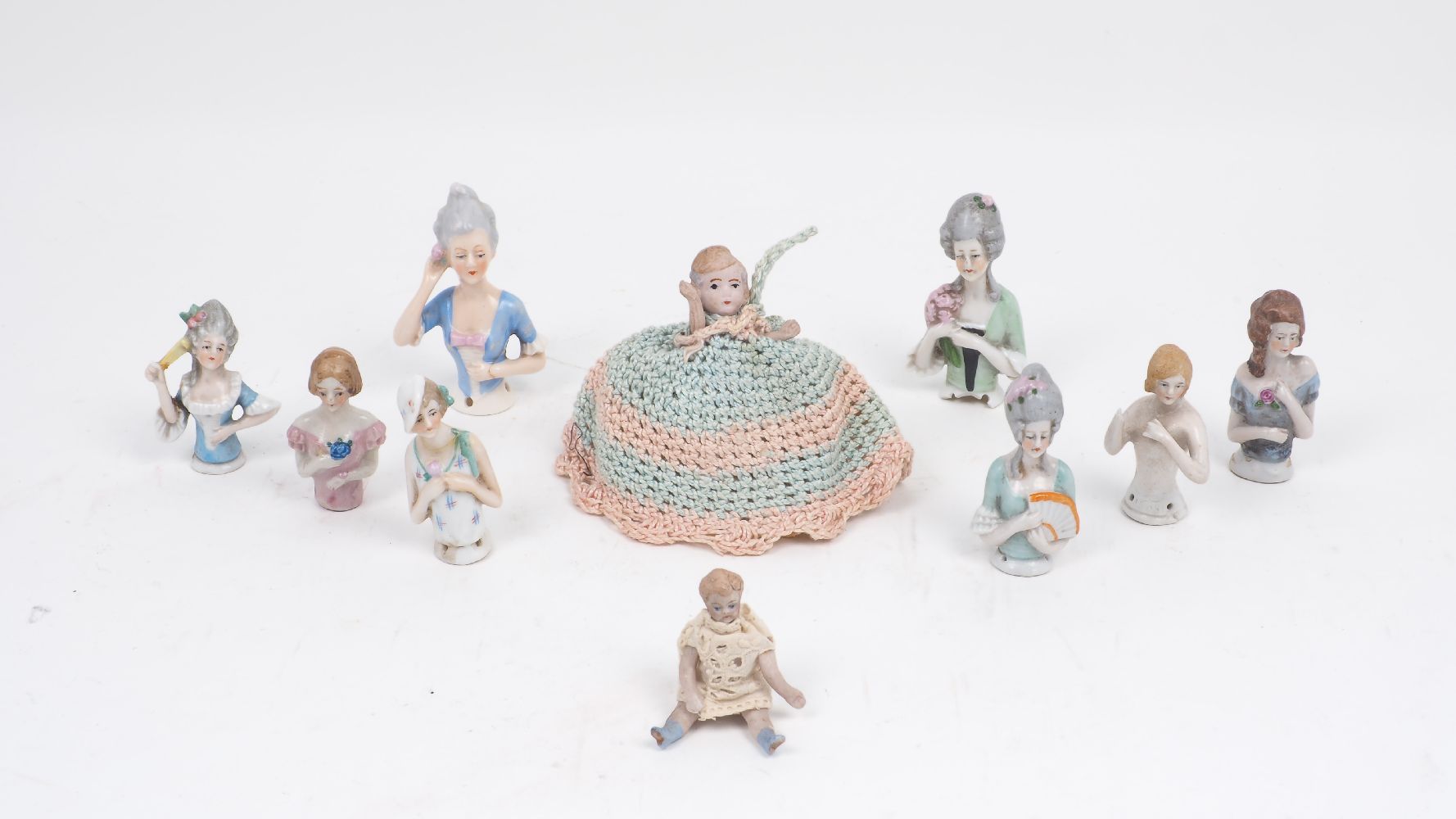 A collection of eight porcelain tea cosy dolls, of various different colour ways and designs,