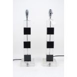 A pair of glass table lamps, each of rising square column form, with recurrent black and clear