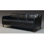 A modern black leather three seater sofa, of recent manufacture, with six loose cushions, on