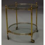 A silvered metal and brass two tier trolley, c.1960, the circular glass top with pierced gallery, on