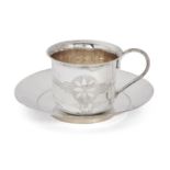 A bright-cut engraved cup and saucer, unmarked white metal, both decorated with flower motif and