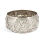 A repousse decorated white metal bowl, possibly Indian, of rounded form, the sides decorated with