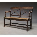 A Regency mahogany and caned settee, the slatted backrest with down swept arms, above caned seat